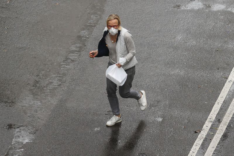 A pedestrian wears a mask while crossing a street in Sydney