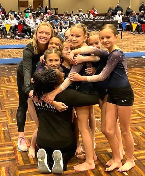 Iliana Grosso of Balance Gymnastics is swarmed by coaches and teammates after recording a perfect 10 in the bars at an illustrious invitational meet.