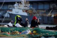 FILE PHOTO: A fisherman repairs a fishing net on the dock of the port in Boulogne-sur-Mer