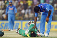 Bangladesh's Mushfiqur Rahim, on ground, reacts in pain after being hit by a ball as India's Varun Aaron tries to comfort him during the Asia Cup one-day international cricket tournament in Fatullah, near Dhaka, Bangladesh, Wednesday, Feb. 26, 2014. (AP Photo/A.M. Ahad)