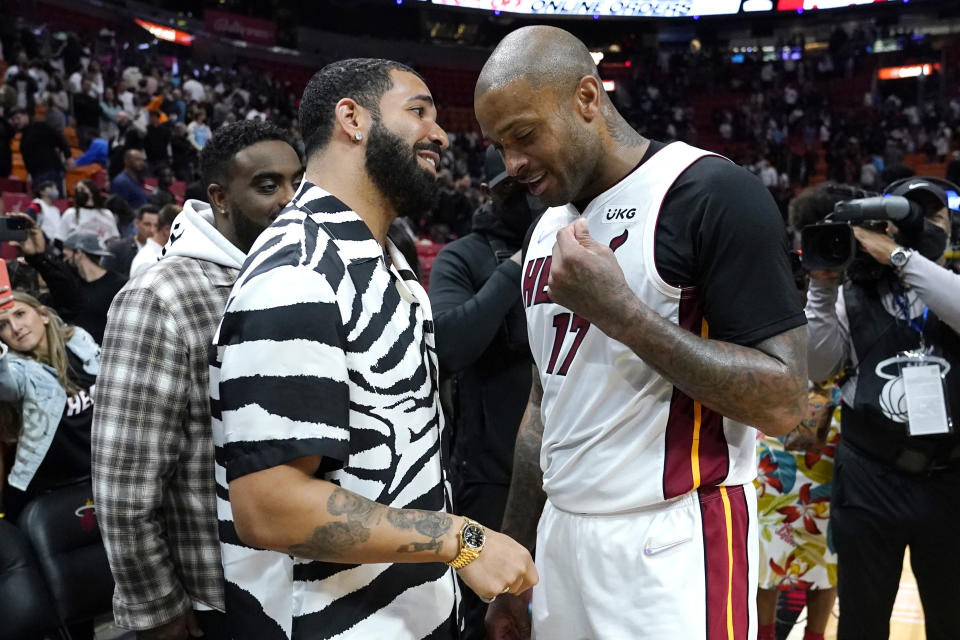 FILE - Musician Drake, left, talks with Miami Heat forward P.J. Tucker, right, after an NBA basketball game against the Atlanta Hawks, Jan. 14, 2022, in Miami. Just as a movie soundtrack helps viewers follow the action of the narrative through each plot twist, hip-hop has done the same for basketball via the NBA. (AP Photo/Lynne Sladky, file)