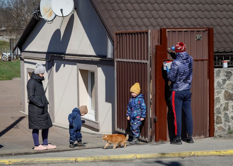 A local family paint the gate of their house on the street where the Russian soldiers killed civilians during occupation in the town of Bucha