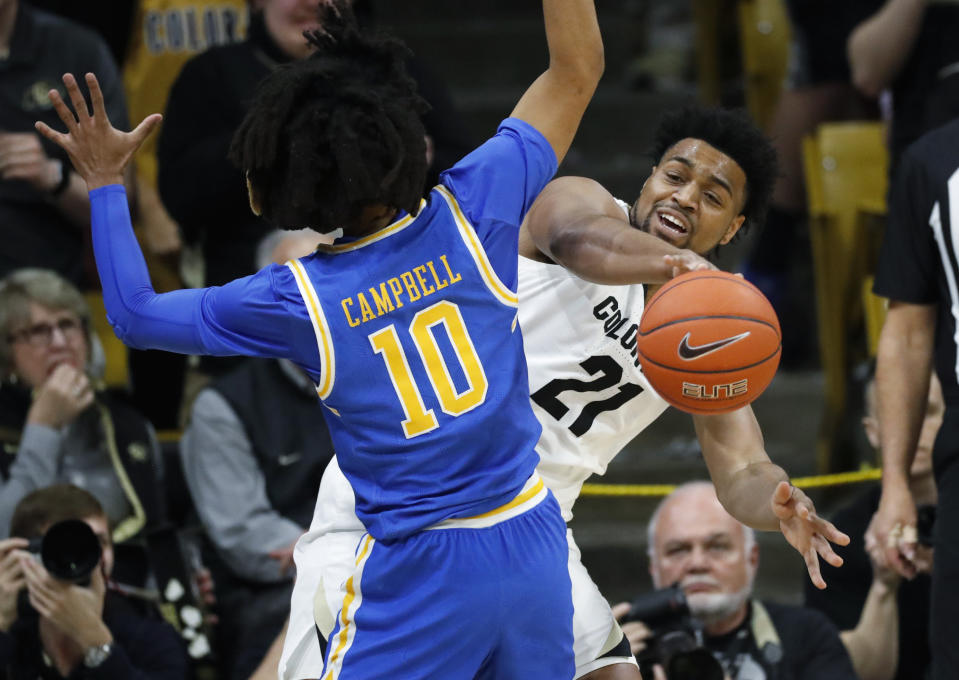 Colorado forward Evan Battey, back, passes the ball as UCLA guard Tyger Campbell defends in the first half of an NCAA college basketball game Saturday, Feb. 22, 2020, in Boulder, Colo. (AP Photo/David Zalubowski)