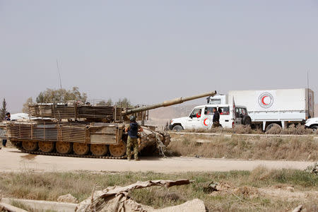 Syrian army military tank and Syrian Arab Red Crescent truck are seen at the entrance of Harasta, in the eastern Damascus suburb of Ghouta, Syria March 22, 2018. REUTERS/Omar Sanadiki