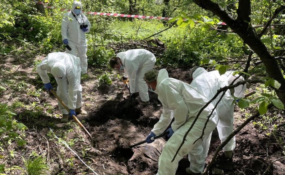 Un equipo forense de Ucrania remueve los restos de un joven soldado enterrado a la afueras de Kiev