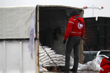 A rebel fighter inspects aid inside Red Crescent vehicles on their way to al Foua and Kefraya, in Idlib province, Syria January 11, 2016. REUTERS/Ammar Abdullah