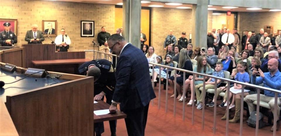 One of six newly promoted Vineland police officers makes his new position official with a signature, as Mayor Anthony Fanucci watches. City Council chambers was packed with families, friends, and other officers for the ceremony. PHOTO: April 8, 2024.