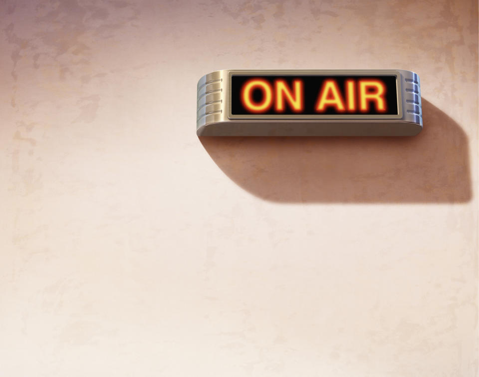 A lit "ON AIR" sign is mounted on a wall, indicating that a live broadcast or recording is in progress