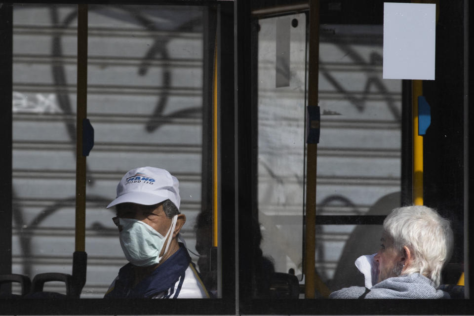 A man wears a face mask as he rides a bus in Tel Aviv, Israel, Sunday, March 15, 2020. Israel has imposed a number of tough restrictions to slow the spread of the new coronavirus. Prime Minister Benjamin Netanyahu announced that schools, universities, restaurants and places of entertainment will be closed to stop the spread of the coronavirus. He also encouraged people not to go to their workplaces unless absolutely necessary. (AP Photo/Oded Balilty)