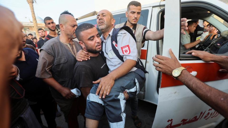 A man carries a wounded Palestinian paramedic in Deir al-Balah, in the central Gaza Strip, on 4 June 2024
