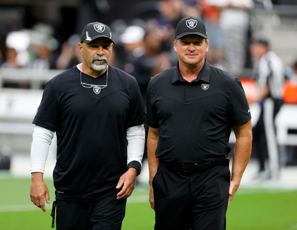 Assistant head coach/special teams coordinator Rich Bisaccia (L) and head coach Jon Gruden of the Las Vegas Raiders talk on the field before their game against the Chicago Bears at Allegiant Stadium on October 10, 2021 in Las Vegas, Nevada.