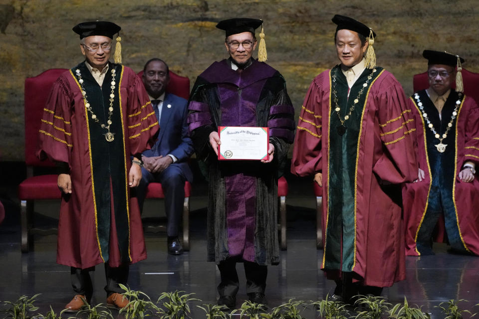 Malaysia's Prime Minister Anwar Ibrahim, center, poses after he was conferred a Doctor of Laws degree, honoris causa, led by Angelo Jimenez, right, president of the University of the Philippines during rites in Quezon city, Philippines on Thursday March 2, 2023. (AP Photo/Aaron Favila)