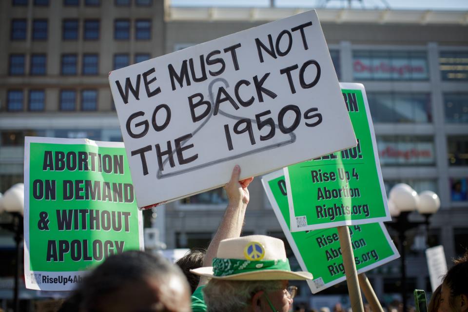 A hand holds a sign: "We must not go back to the 1950s"