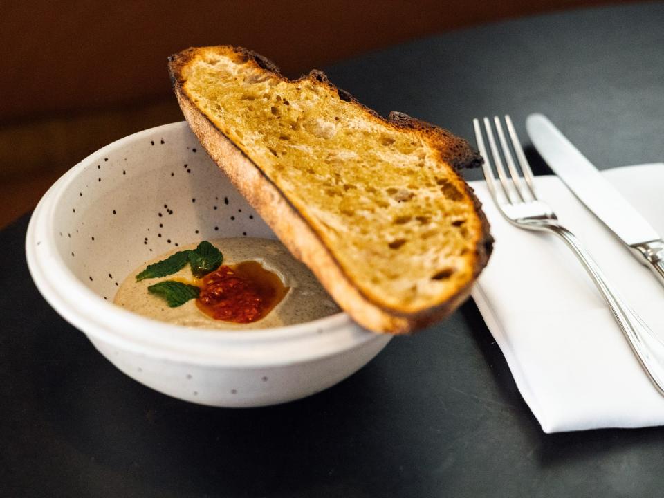 a bowl with smoked eggplant, hot chile, yogurt, and mint with a slice of toast