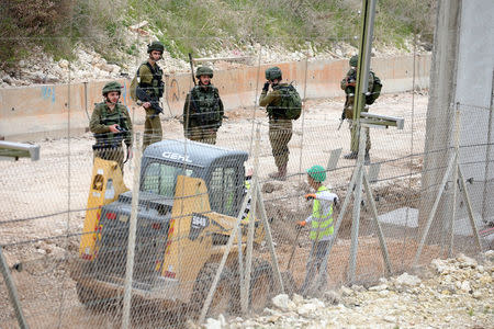 Israeli workers are seen building a wall near the border with Israel near the village of Naqoura, Lebanon February 8, 2018. REUTERS/Ali Hashisho