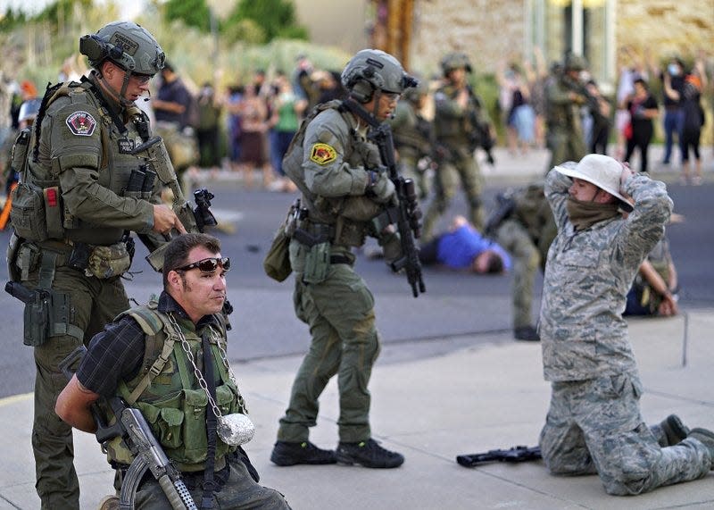 Albuquerque police detain members of the New Mexico Civil Guard, an armed civilian group, following the shooting of a man during a protest over a statue of Spanish conquerer Juan de Oñate on Monday, June 15, 2020, in Albuquerque, N.M.