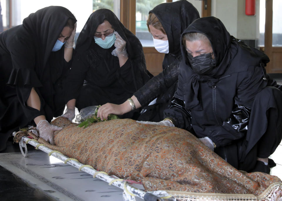 Relatives mourn over the body of a person who died from COVID-19 at the Behesht-e-Zahra cemetery just outside Tehran, Iran, Sunday, Nov. 1, 2020. The Behesht-e-Zahra, or “Zahra’s Paradise” in Farsi, named after a daughter of the Prophet Muhammad — is struggling to keep up with the coronavirus pandemic ravaging the country. (AP Photo/Ebrahim Noroozi)