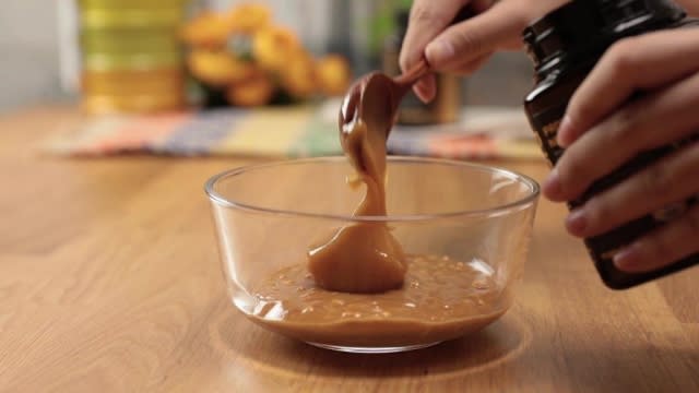 Scooping manuka honey into a sauce