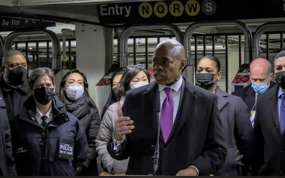 Mayor Eric Adams, foreground, with city law officials, speaks at a news conference inside a subway station after a woman was pushed to her death in front of a subway train - NYPD News via AP