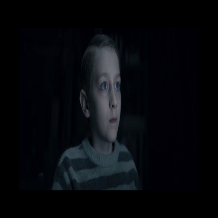 A child in a dark room with his face lit by a screen