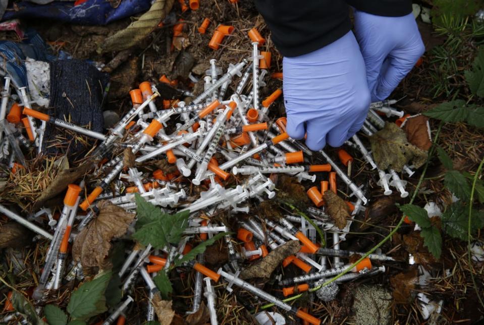 A volunteer cleans up needles used for drug injection that were found at a homeless encampment in Everett, Wash., Nov. 8, 2017. A temporary law that makes possession of small amounts of drugs a misdemeanor expires on July 1, so if lawmakers fail to pass a bill, Washington would become the second state — after neighboring Oregon — to decriminalize drug possession. Lawmakers said Tuesday, May 2, 2023, they were increasingly optimistic a compromise will be reached to avoid those consequences. (AP Photo/Ted S. Warren, File)