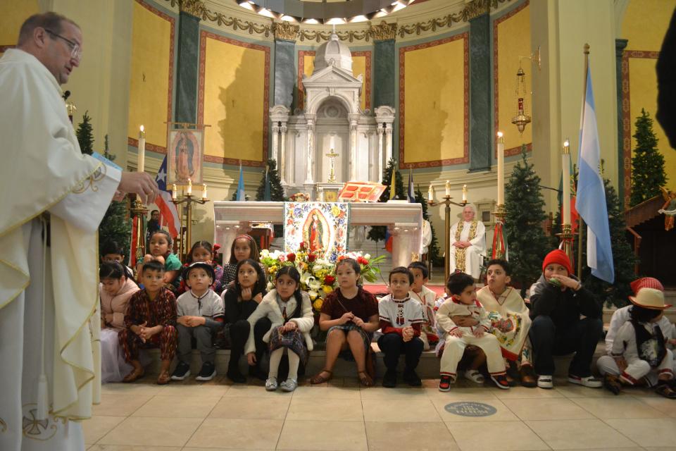 Father Scott Pontes, who celebrates the weekly Spanish Mass at St. Joseph's Church in Newport, called all the children up to the front of the church to learn the story behind the Feast Day of Our Lady of Guadalupe on Sunday Dec. 18, 2022. The apse of the church was decorated with flags from various Latin American countries.