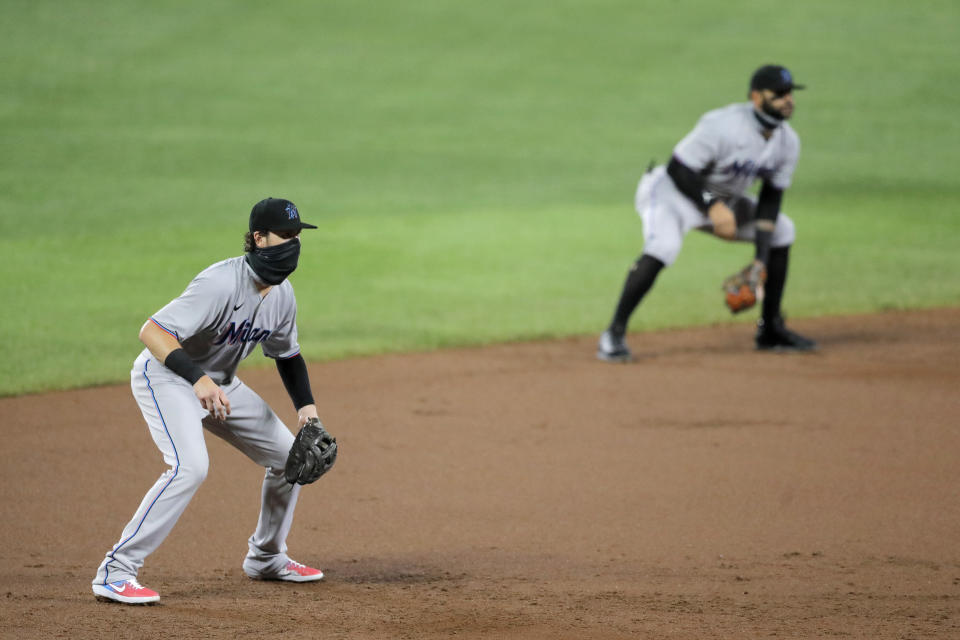 Miami Marlins third baseman Brian Anderson, left, wears a face mask to protect against COVID-19 while in the ready position next to shortstop Jonathan Villar during the second inning of a baseball game against the Baltimore Orioles, Tuesday, Aug. 4, 2020, in Baltimore. (AP Photo/Julio Cortez)