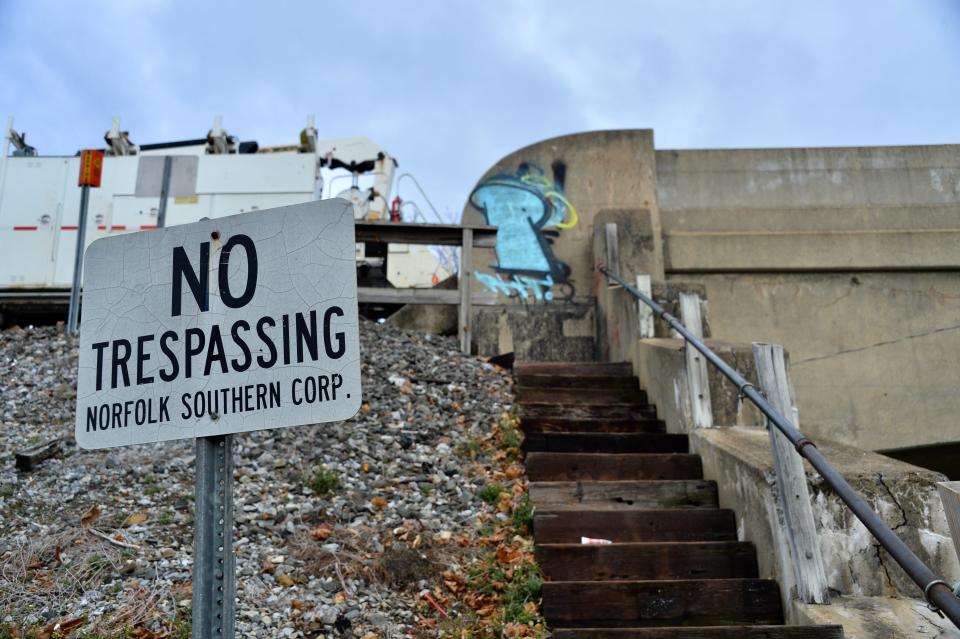 A Norfolk Southern "No Trespassing" sign warns pedestrians not to use an open staircase along Church Street to the railroad overpass parallel to North Burhans Boulevard.