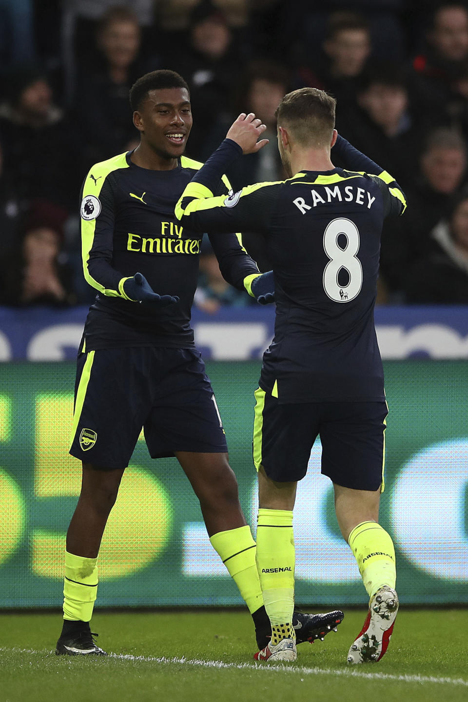 Arsenal's Alex Iwobi, left, celebrates his side's second goal of the game after his shot was deflected resulting in a own goal for Swansea City's Jack Cork during the English Premier League soccer match between Swansea City and Arsenal at the Liberty Stadium, Swansea, Wales, Saturday, Jan. 14, 2017.(Nick Potts/PA via AP)