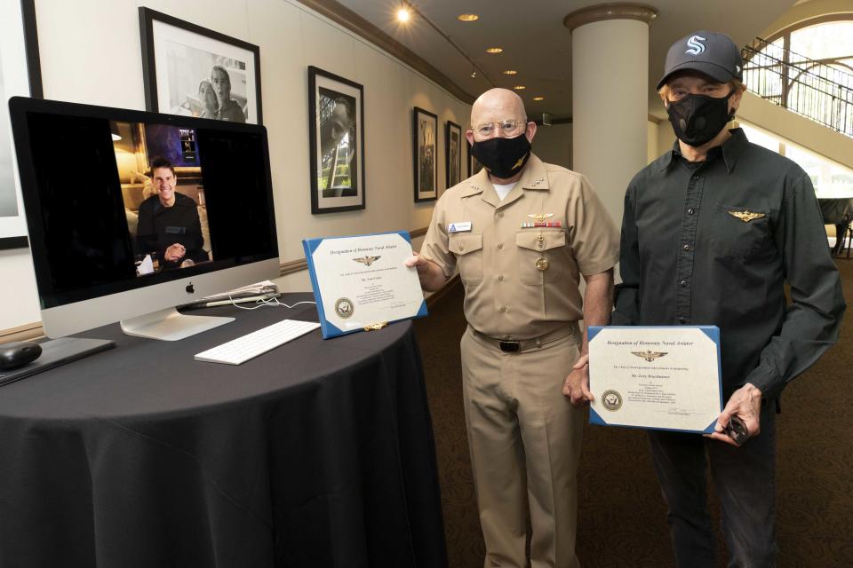 Vice Adm. DeWolfe H. Miller III (c), Commander, U.S. Naval Air Forces, presents Honorary Naval Aviator designations to actor Tom Cruise (l), and film producer Jerry Bruckheimer (r), in recognition of their significant and continuous support of Naval Aviation throughout the production of films Top Gun and Top Gun: Maverick (Credit: U.S. Navy photo by Alex J. Berliner)