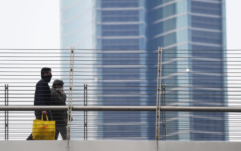 People wearing protective face masks walk as the spread of coronavirus disease (COVID-19) continues, in Milan