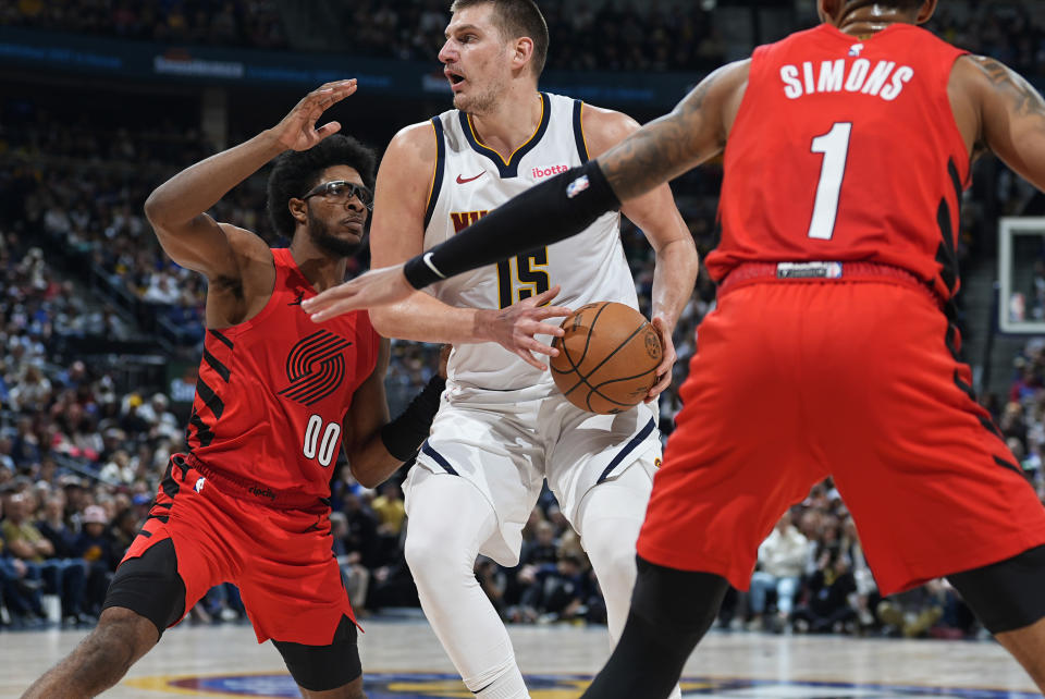Denver Nuggets center Nikola Jokic, center, drives the lane as Portland Trail Blazers guards Scoot Henderson, left, and Anfernee Simons defend in the second half of an NBA basketball game Sunday, Feb. 4, 2024, in Denver. (AP Photo/David Zalubowski)