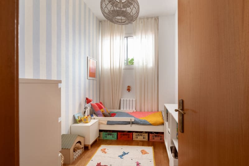 Kids room with blue and white striped walls, small bed with storage underneath