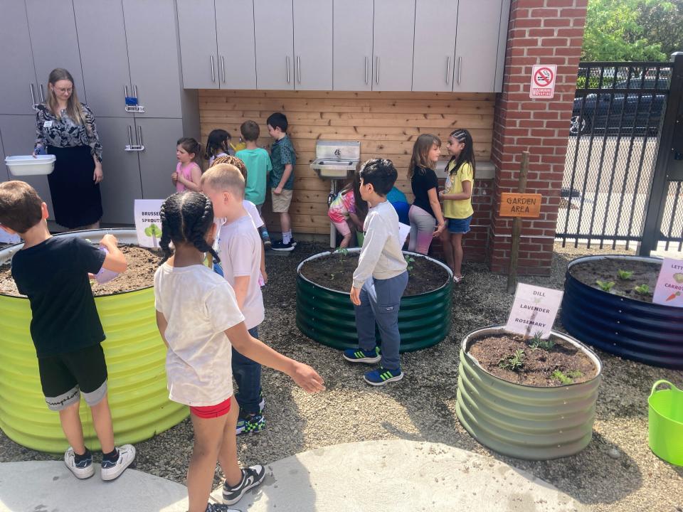 First-grade students from Belle Valley Elementary School water plants in raised beds in the outdoor classroom at Experience Children's Museum.