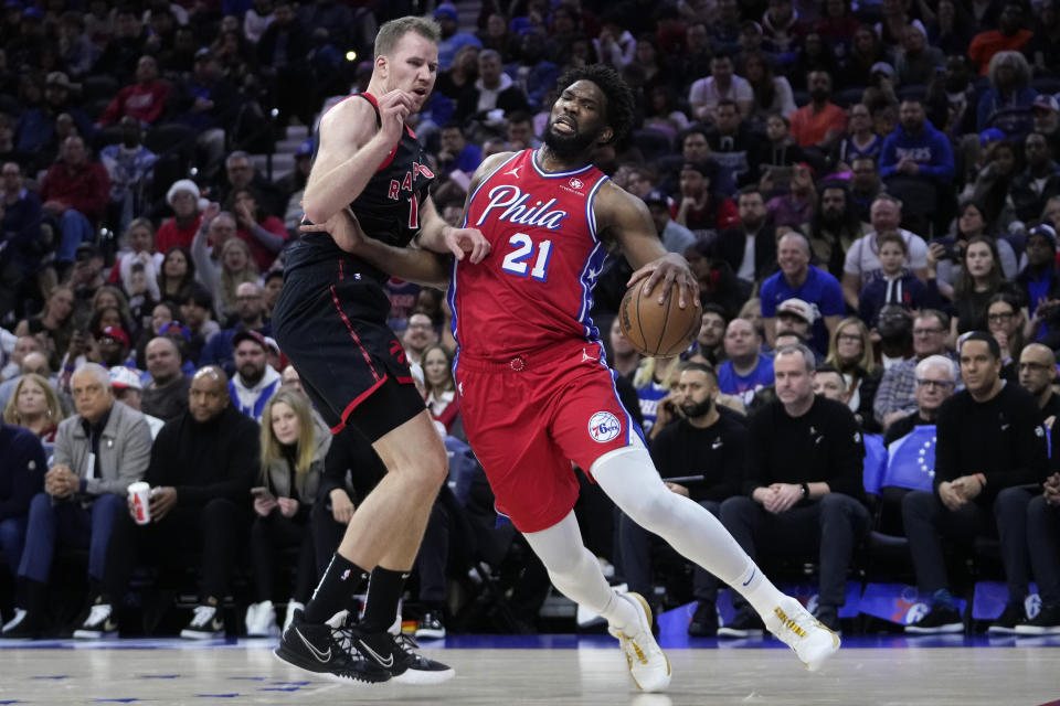 Philadelphia 76ers' Joel Embiid, right, tries to get past Toronto Raptors' Jakob Poeltl during the first half of an NBA basketball game, Friday, Dec. 22, 2023, in Philadelphia. (AP Photo/Matt Slocum)