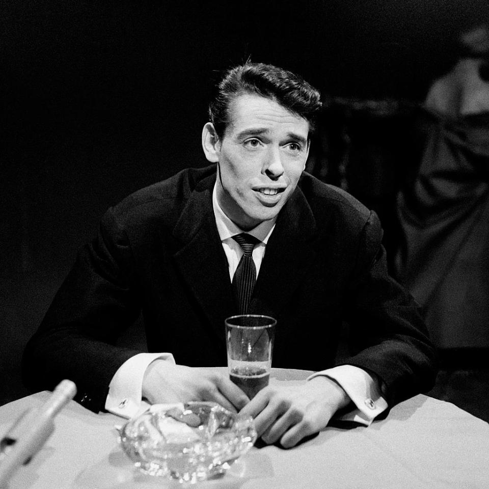 Fort heureusement, Jacques Brel se rattrape dès le lendemain, et l’attend devant chez avec un petit bouquet de fleurs à la main. Durant trois heures, le grand échalas va faire le pied de grue sous une pluie glacée, jusqu’à ce que Thérèse le remarque et descende pour le remercier. Les deux tourtereaux échangent alors leur premier baiser. (<em>Philippe Bataillon\INA via Getty Images</em>)