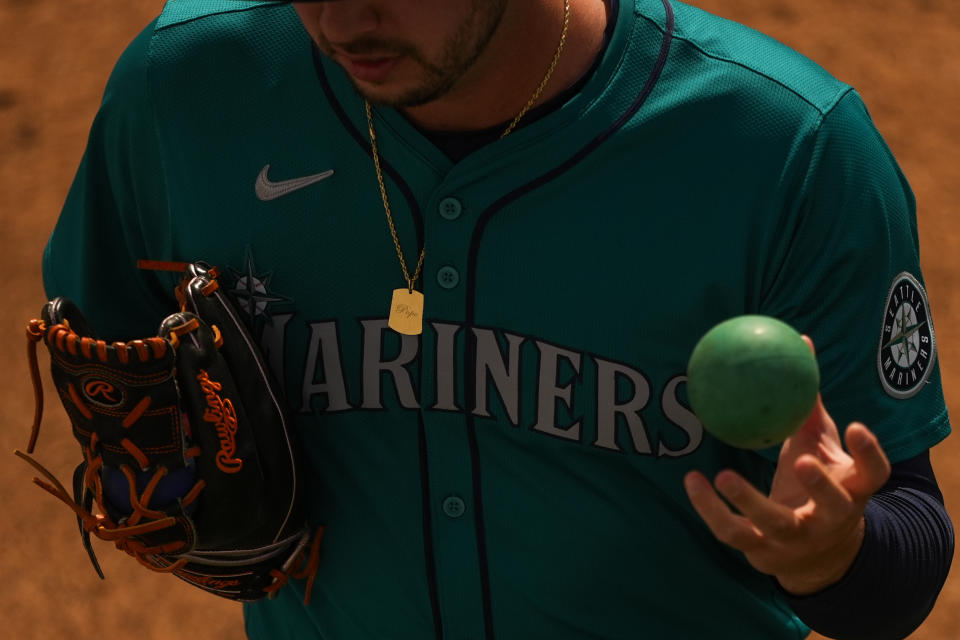 FILE - Seattle Mariners relief pitcher Tayler Saucedo uses a weighted ball to warm up in the bullpen before a spring training baseball game against the Kansas City Royals, March 6, 2024, in Surprise, Ariz. Velocity training is the rage in baseball from the youth levels up through the majors. Players go through specialized programs – often using series of progressively weighted baseballs – in the hopes of speeding up their bodies and arms, pushing them to the limits of what might be possible for their age and ability. (AP Photo/Lindsey Wasson, File)