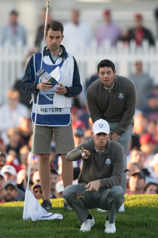 Thomas Pieters of Belgium (C) lines up a putt with his partner Rory McIlroy of Northern Ireland while playing the morning foursomes matches