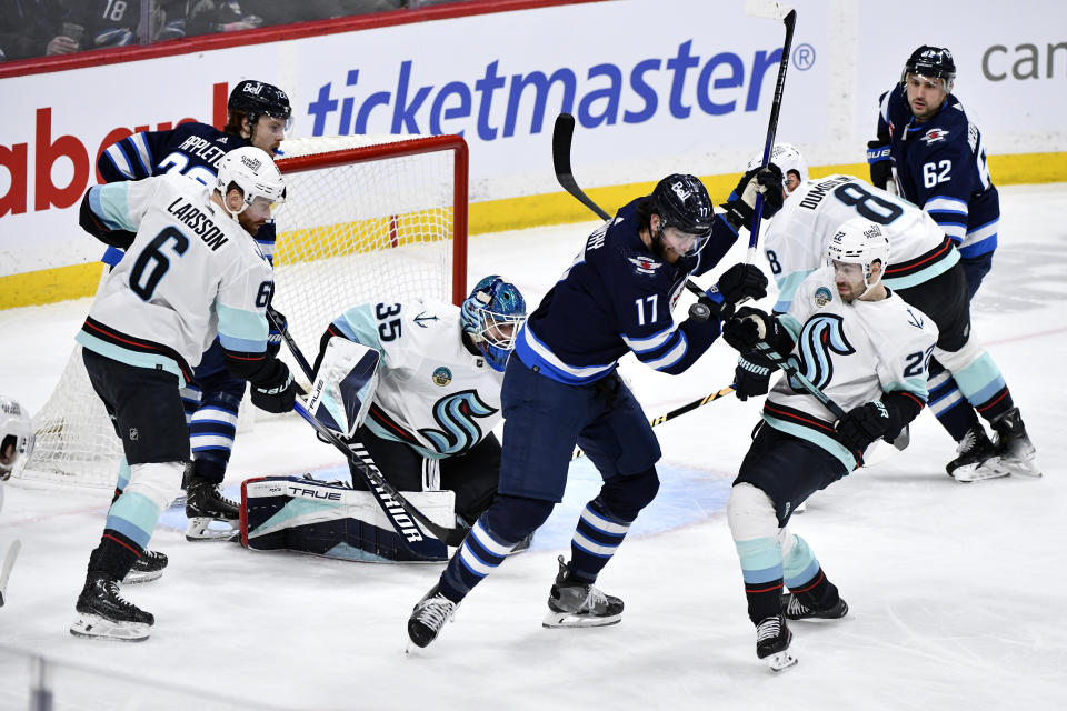 Seattle Kraken's Oliver Bjorkstrand (22) and Winnipeg Jets' Adam Lowry (17) vie for the puck during the third period of an NHL hockey game Tuesday, March 5, 2024, in Winnipeg, Manitoba. (Fred Greenslade/The Canadian Press via AP)