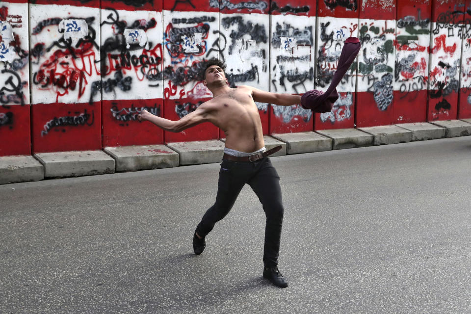 A protester throws stones towards the central bank building in Beirut, Lebanon, Saturday, March. 13, 2021. Riot police fired tear gas to disperse scores of people who protested near parliament building in central Beirut Saturday amid deteriorating economic and financial conditions and as the local currency hit new low levels. (AP Photo/Bilal Hussein)