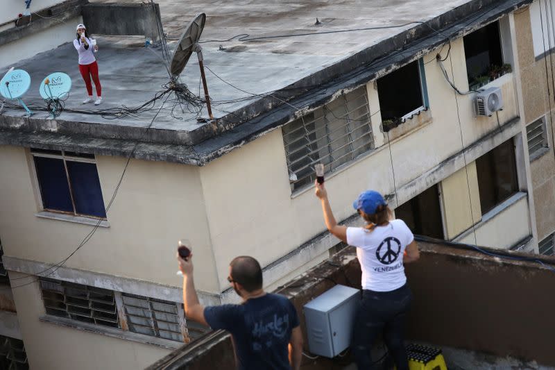 Neighbors cheer from different rooftops during a nationwide quarantine due to the coronavirus disease (COVID-19) outbreak in Caracas