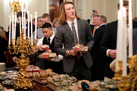 Clemson's quarterback Trevor Lawrence carries fast food hamburgers provided due to the partial government shutdown as the 2018 College Football Playoff National Champion Clemson Tigers are welcomed in the State Dining Room of the White House in Washington, U.S., January 14, 2019. REUTERS/Joshua Roberts