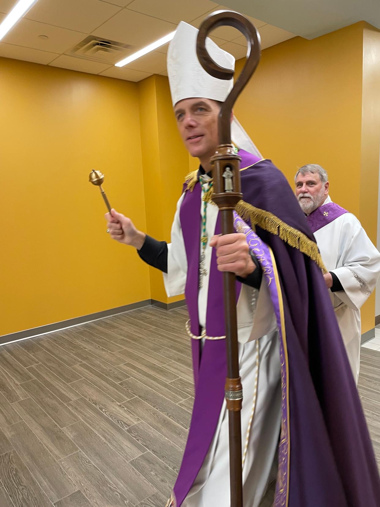 Accompanied by church Deacon Kerry Diver (right), Bishop Stephen D. Parkes of the Diocese of Savannah uses an aspergillum to sprinkle holy water down a hallway of one of the newly-constructed buildings at St. Teresa of Avila Catholic Church in Grovetown.