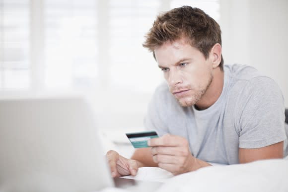 a man enters credit card information into his laptop.