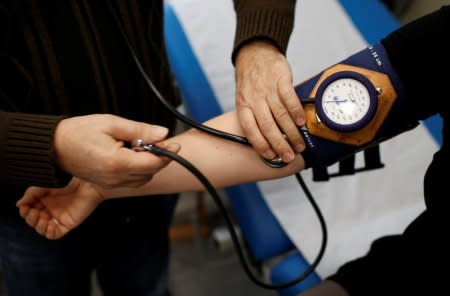 Retired French doctor Jean-Francois Rechner, 67, measures the blood pressure of a patient during a consultation at the 'Service Medical de Proximite' clinic in Laval, France, November 8, 2018. Picture taken November 8, 2018. REUTERS/Stephane Mahe