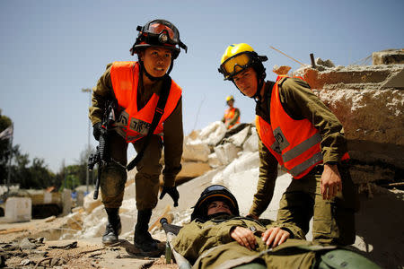 Joana Chris Arpon (L), an Israeli soldier from a search and rescue unit, whose parents immigrated from the Philippines, helps evacuate her comrade during a drill at Tzrifin military base in central Israel May 10, 2017. REUTERS/Amir Cohen