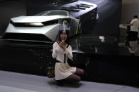 A live streamer poses near a concept car from Nissan during Auto China 2024 held in Beijing, Thursday, April 25, 2024. Global automakers and EV startups unveiled new models and concept cars at China's largest auto show on Thursday, with a focus on the nation's transformation into a major market and production base for digitally connected, new-energy vehicles. (AP Photo/Ng Han Guan)