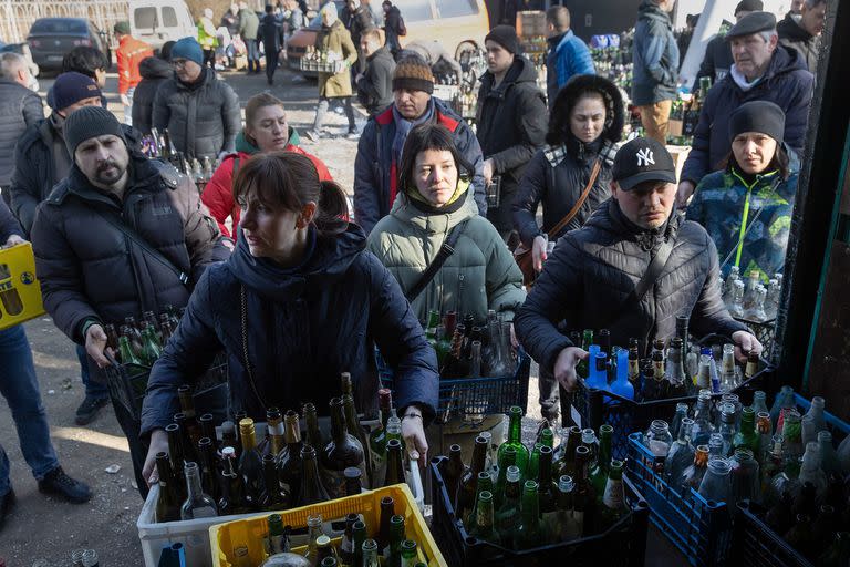 Civiles voluntarios preparan botellas vacías donadas para ser usadas como cócteles Molotov en un centro de recolección ubicado en un estacionamiento de Dnipro, Ucrania, el 27 de febrero de 2022.