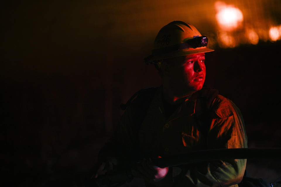 A Cal Fire/Riverside County Fire Department firefighter surveys for instructions while battling wildfire in rural Aguanga, Calif. Monday, Oct. 30, 2023. (Anjali Sharif-Paul/The Orange County Register via AP)