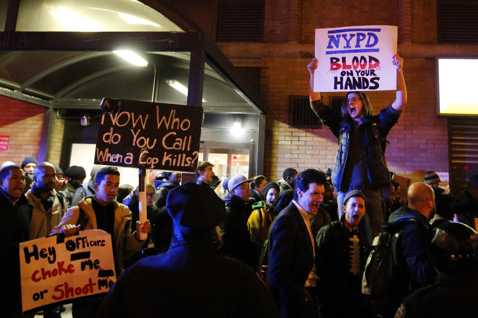 Protesters rallying against a grand jury's decision not to indict the police officer involved in the death of Eric Garner chant as they pass police while marching through Midtown in the early morning hours of Friday, Dec. 5, 2014, in New York. (AP Photo/Jason DeCrow)